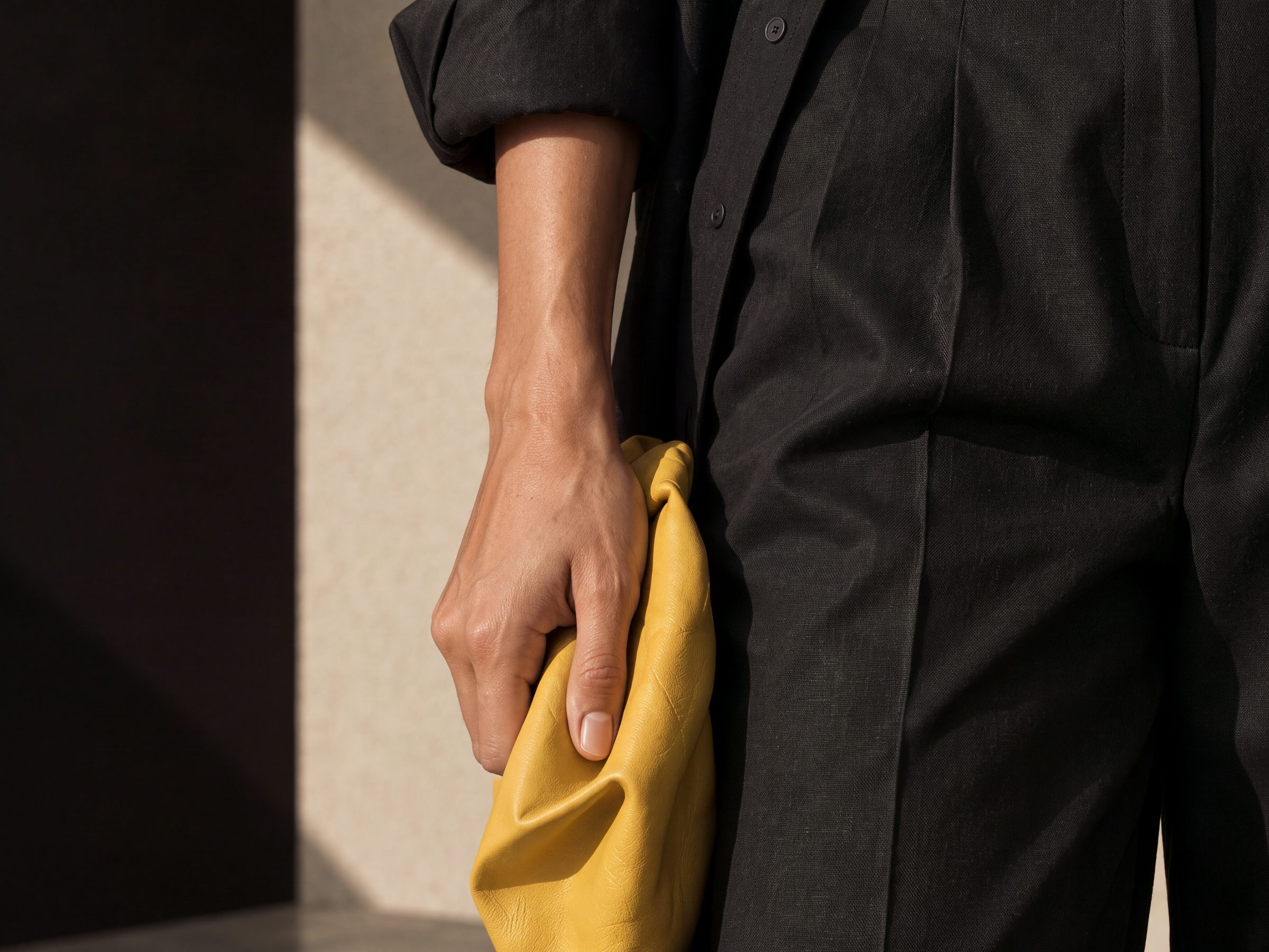 Close-up of a hand holding a yellow leather clutch